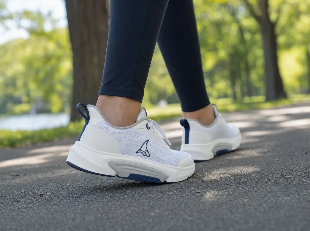 A woman in her seventies walking a garden path in B-Active, the sole reading against the paving.