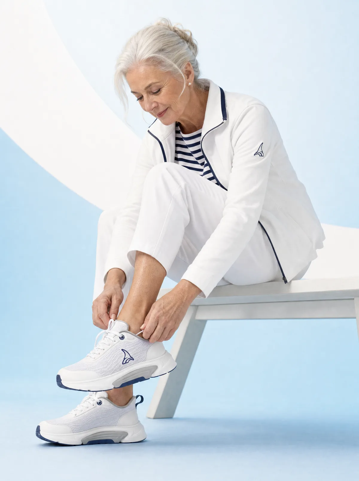A woman in her seventies easing her foot into a B-Active on a pale bench, shot on PAHI’s own brand ground.